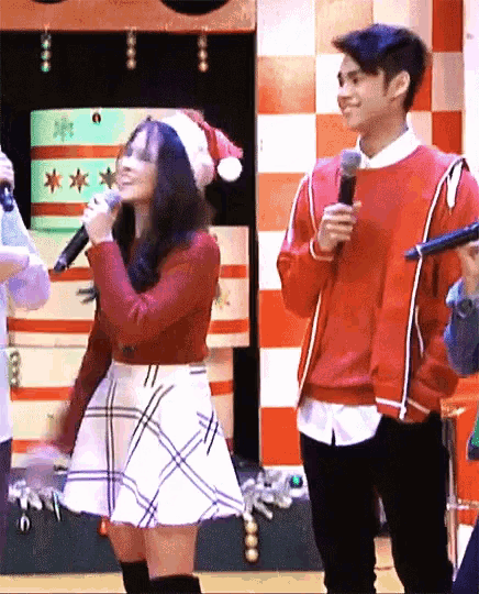 a woman in a santa hat sings into a microphone