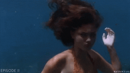 a woman in an orange bikini is swimming underwater in the ocean .
