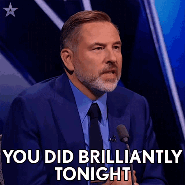 a man in a suit and tie is talking into a microphone and says you did brilliantly tonight