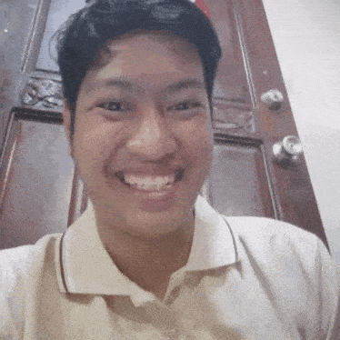 a man wearing a white shirt is smiling in front of a door