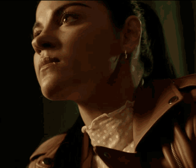 a close up of a woman 's face with a ponytail and earrings