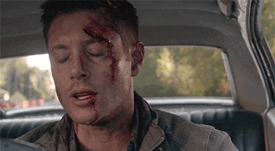 a man with a bloody face is sitting in the back seat of a car with his eyes closed .