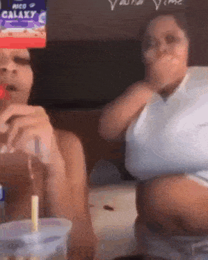 two women are sitting in front of a galaxy box .
