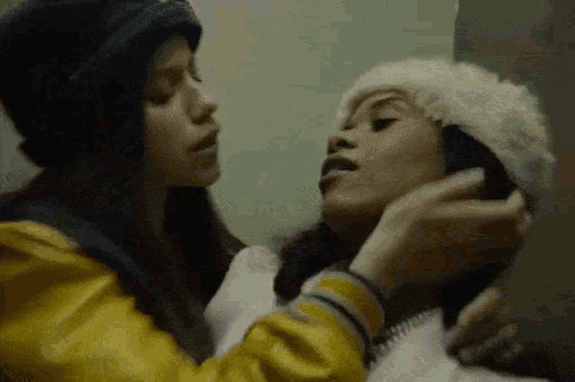 two women are standing next to each other and one is wearing a hat .