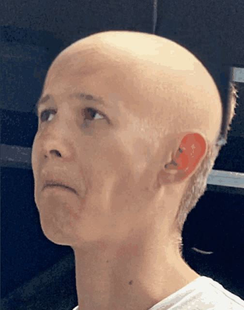 a close up of a bald man 's face with a white shirt on