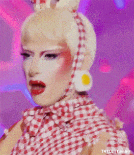 a drag queen wearing a red and white checkered shirt and earrings with an egg on her head .