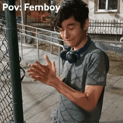 a man wearing headphones applauds in front of a chain link fence