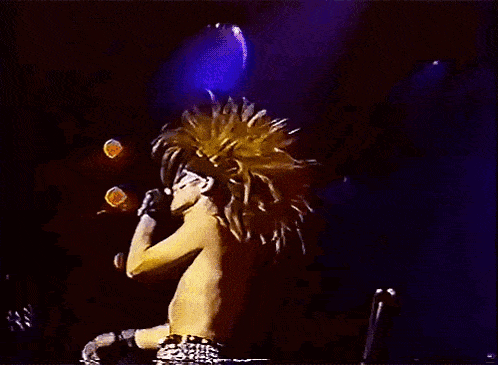 a shirtless man is singing into a microphone on stage .