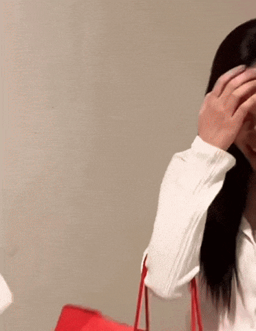 a woman in a white shirt is covering her face with her hands