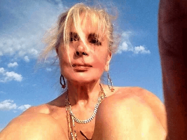 a woman wearing a necklace and earrings is taking a selfie
