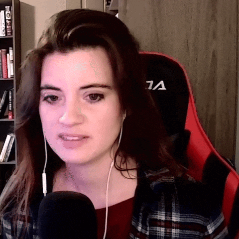 a woman wearing headphones and a plaid shirt is sitting in a red gaming chair with the letter a on it