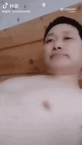 a man without a shirt is making a funny face while laying on a bed .