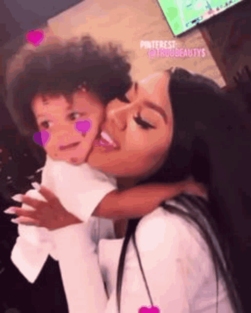 a woman is holding a small child in her arms and kissing him on the cheek .