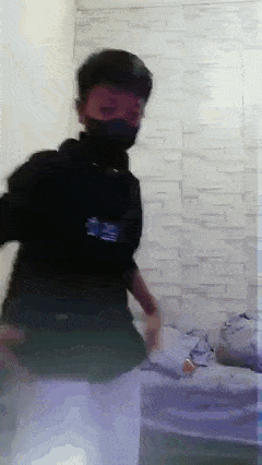 a man wearing a mask is standing in a room with a brick wall .