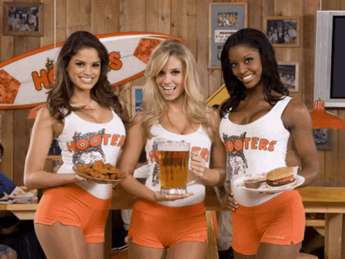 three hooters waitresses holding plates of food and a beer
