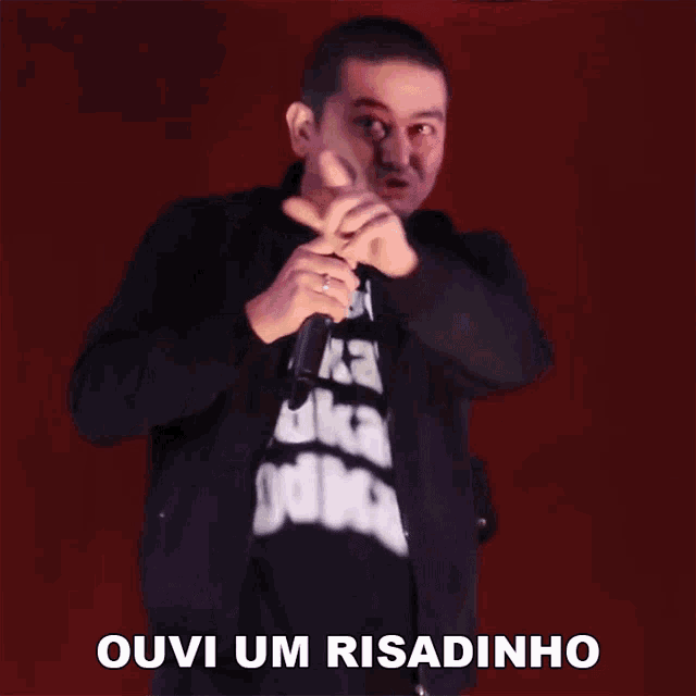 a man holding a microphone with the word ouvi um risadinho written below him