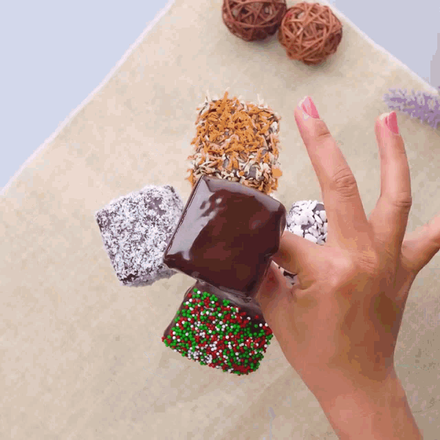 a hand is holding a stack of chocolate covered treats with sprinkles