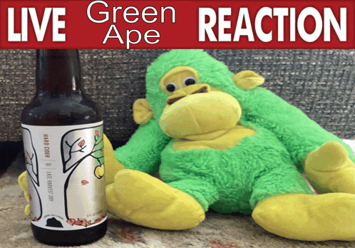 a stuffed green monkey sitting next to a bottle of green ape