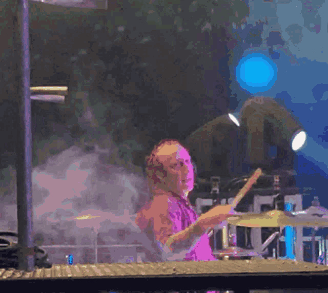 a man is playing drums in front of a blue light