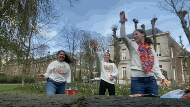 a woman wearing a shirt that says ' hawaii ' on it stands in front of two other women