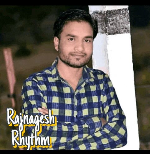 a man in a plaid shirt stands with his arms crossed in front of a sign that says rajnajesh rhythm