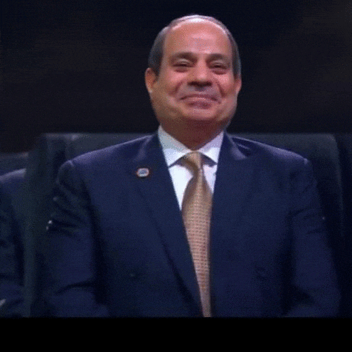 a man in a suit and tie is smiling and laughing .