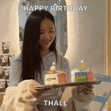 a woman is holding a tray with a birthday cake on it and says happy birthday thall .
