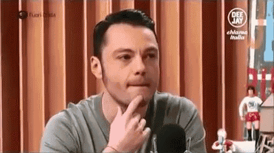 a man is sitting in front of a microphone and thinking about something .