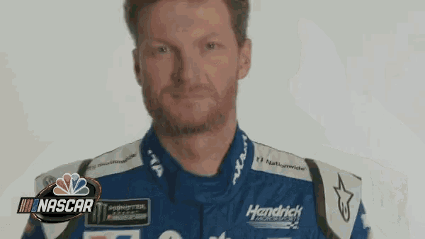 a man with a mustache is wearing headphones and a nascar logo on his shirt .