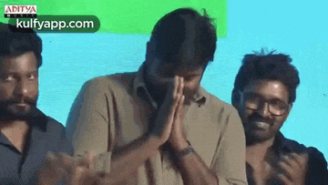 a man is covering his face with his hands while standing in front of a group of men .