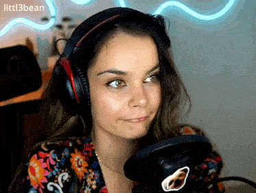 a woman wearing headphones stands in front of a microphone with litl3bean written on the bottom right