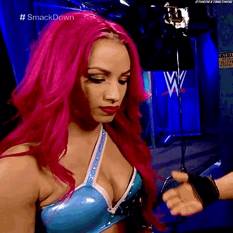 a woman with pink hair is standing in front of a sign that says #smackdown