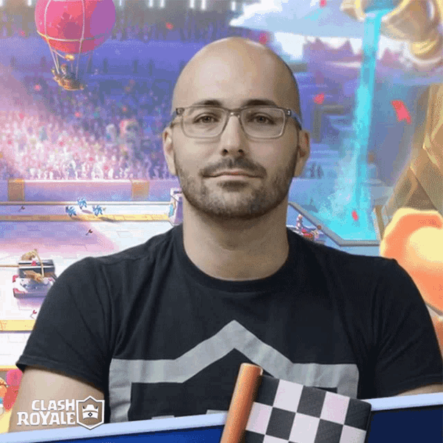 a man wearing glasses and a clash royale t-shirt holds a checkered flag