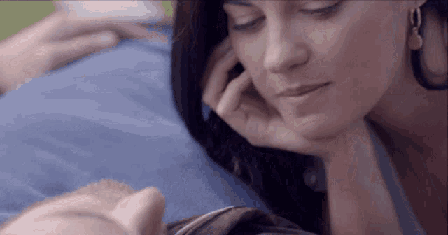 a close up of a woman looking at a baby laying on a bed