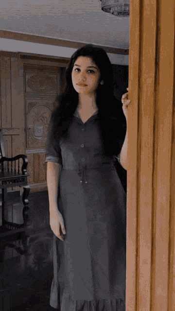 a woman in a grey dress is standing in a room