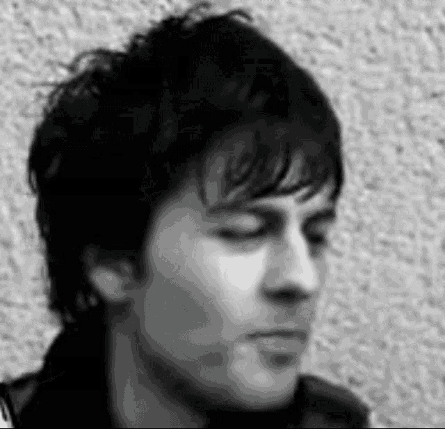 a black and white photo of a young man 's face with his eyes closed .