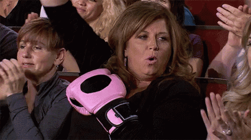 a woman is wearing a pink boxing glove while sitting in a crowd .