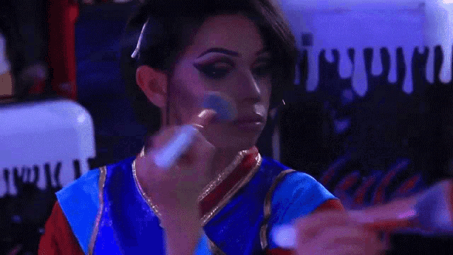 a woman is applying makeup in front of a sign that says ' www ' on it