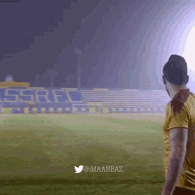 a man stands on a soccer field in front of a stadium with ssrfc written on the bleachers