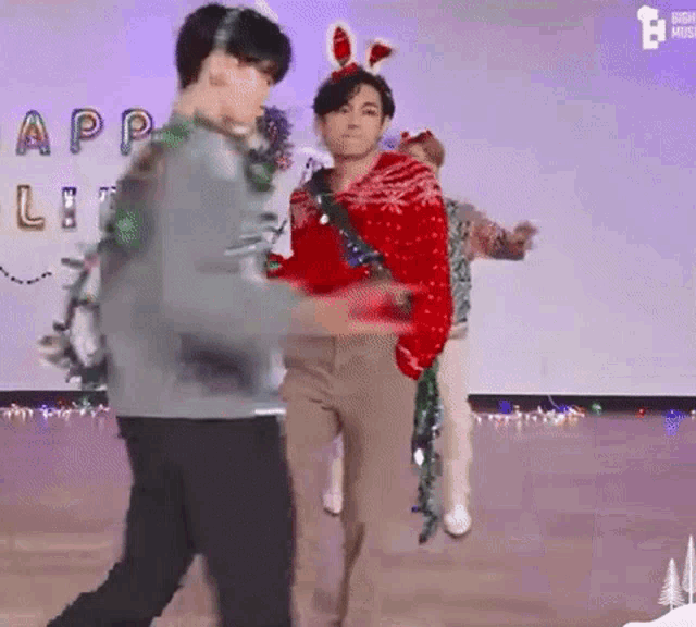 a group of men are dancing on a stage while wearing christmas sweaters .