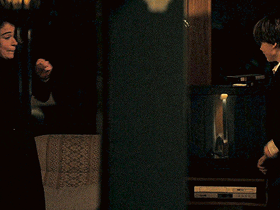 a man and a woman are standing next to each other in a dark room and the man is holding a gun