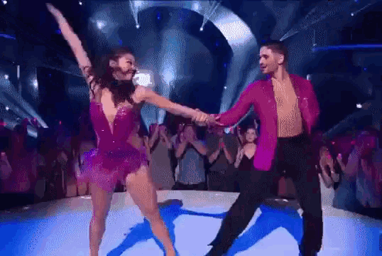 a man and a woman are dancing on a stage with a crowd watching