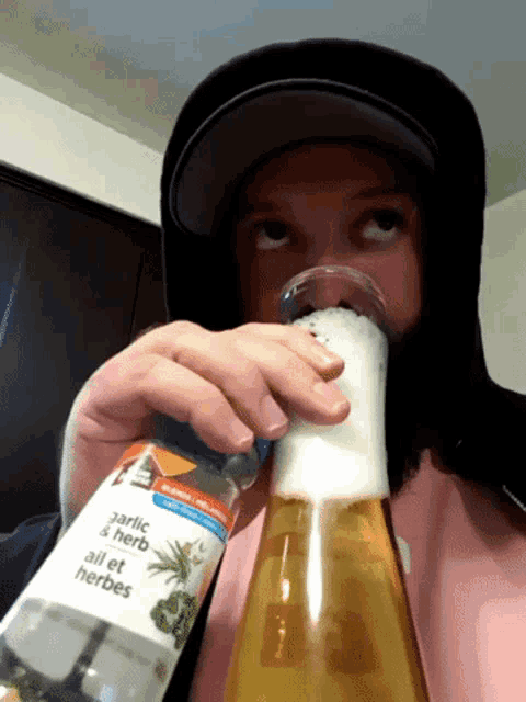 a person drinking from a bottle that says garlic and herb