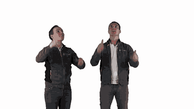two men are holding up their phones in the air and pointing up .
