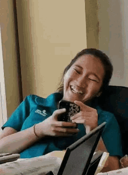 a woman wearing a shirt that says ' jesus ' on it is smiling while holding a cell phone