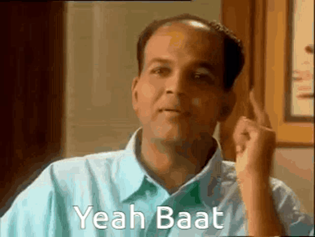 a bald man in a blue shirt is making a funny face and says yeah baat .
