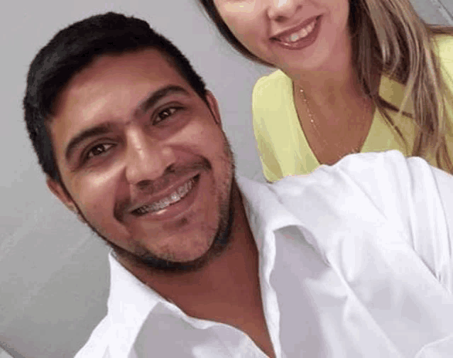 a man and a woman are posing for a picture and smiling . the man is wearing braces on his teeth .