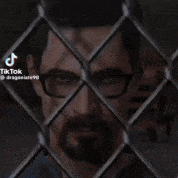 a man with glasses is behind a chain link fence with a lightning bolt coming out of it .