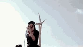 a woman is singing into a microphone while a man plays a guitar behind her .