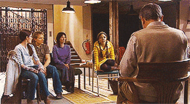 a group of people sitting around a table with a man sitting in a chair